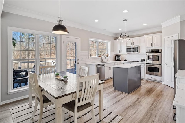 kitchen featuring a kitchen island, stainless steel appliances, light wood-style floors, light countertops, and decorative backsplash