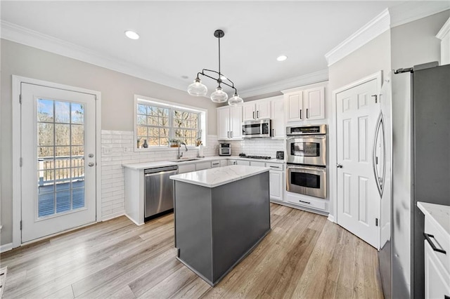 kitchen featuring white cabinets, stainless steel appliances, light wood-style floors, and a sink