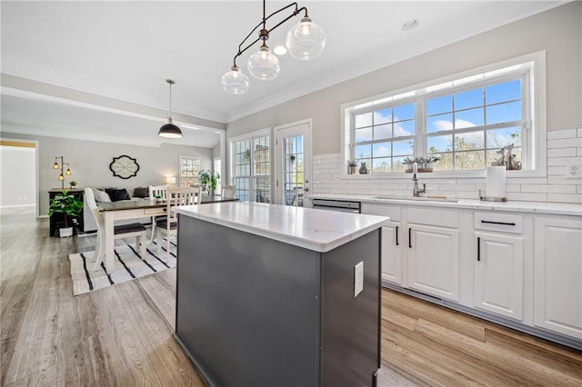 kitchen featuring a sink, tasteful backsplash, a kitchen island, light wood-style floors, and white cabinets