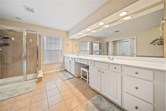 full bath with tile patterned floors, visible vents, a shower stall, double vanity, and baseboards