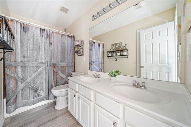 bathroom with double vanity, toilet, visible vents, and a sink