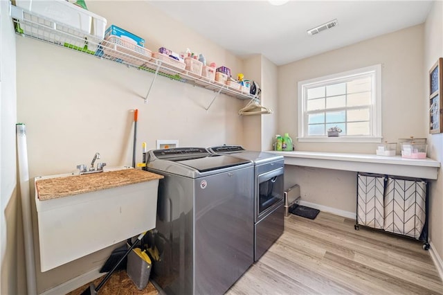 clothes washing area with baseboards, visible vents, laundry area, light wood-style flooring, and washer and dryer