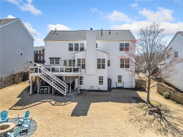 rear view of property featuring a fenced backyard, a chimney, stairs, a fire pit, and a deck