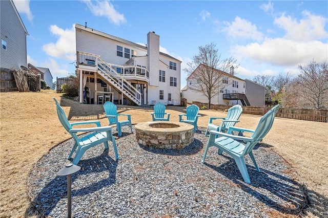 rear view of house featuring a wooden deck, stairway, fence, and an outdoor fire pit