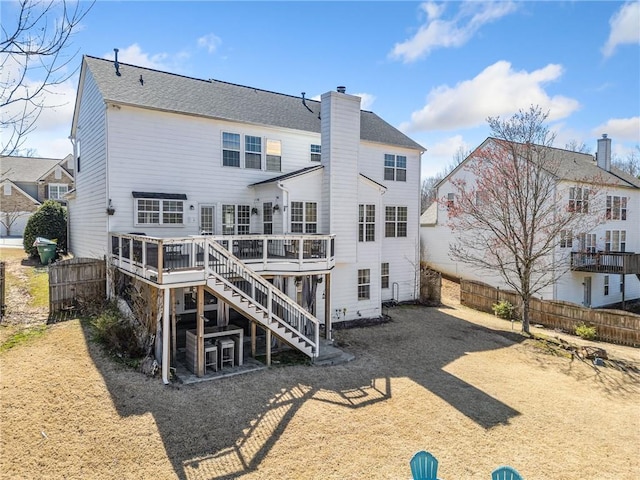 rear view of house featuring a deck, stairway, fence, and a chimney