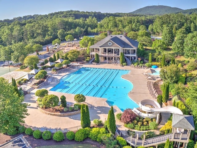 pool featuring a forest view, stairs, a patio, and fence