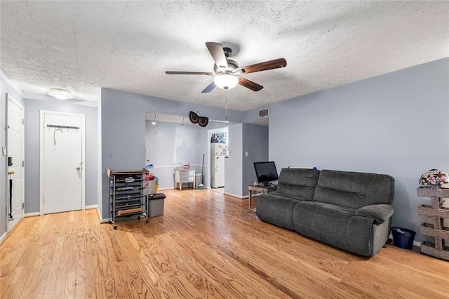 living room featuring ceiling fan, light hardwood / wood-style flooring, and a textured ceiling