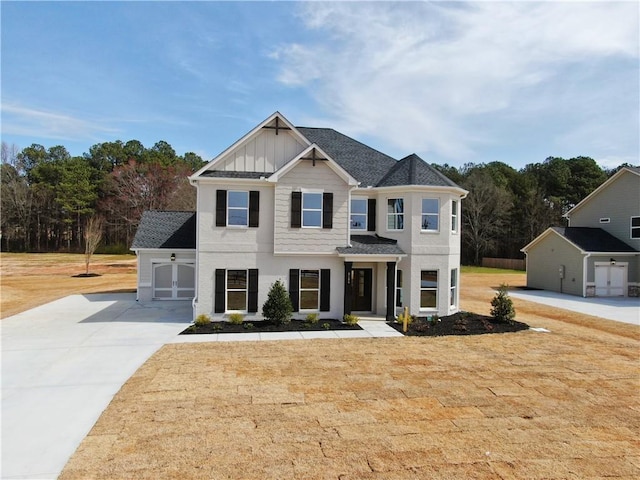 view of front of property featuring a garage, a shingled roof, driveway, board and batten siding, and a front yard