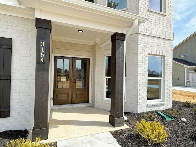 doorway to property featuring french doors and brick siding