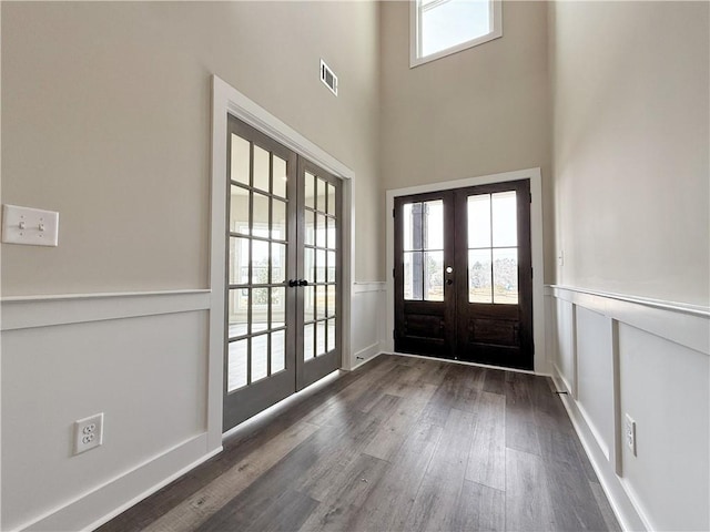 entrance foyer featuring visible vents, wainscoting, dark wood-style floors, french doors, and a decorative wall