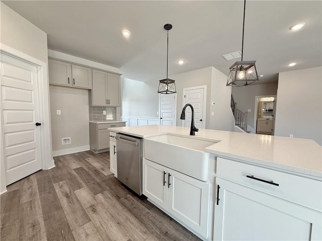 kitchen with recessed lighting, visible vents, stainless steel dishwasher, a sink, and wood finished floors