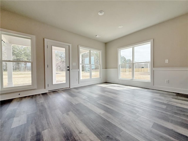 interior space with dark wood-style flooring, a wainscoted wall, and visible vents