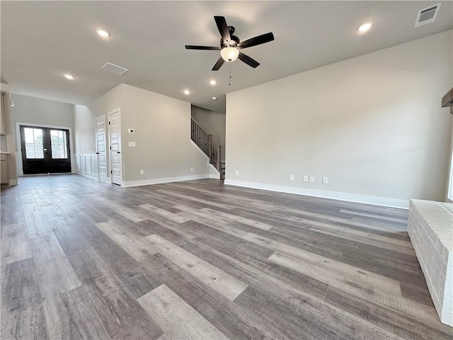 unfurnished living room with stairs, visible vents, and baseboards