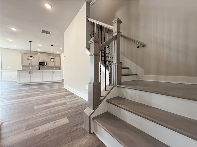 stairway featuring recessed lighting, visible vents, baseboards, and wood finished floors