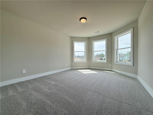 empty room with carpet flooring, visible vents, and baseboards