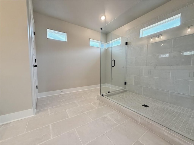 bathroom featuring tile patterned flooring, plenty of natural light, a shower stall, and baseboards