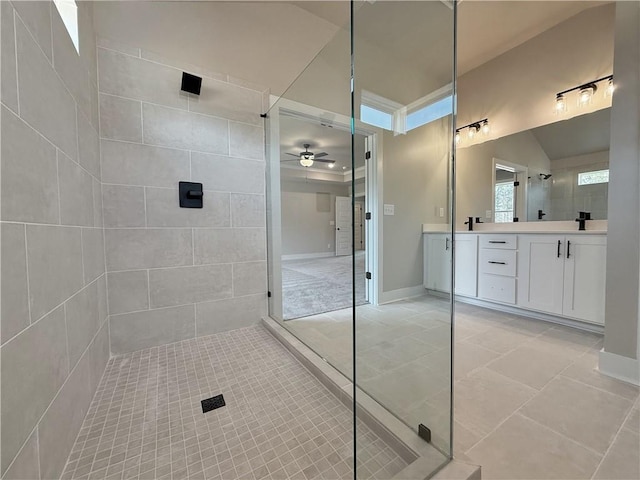 bathroom with tile patterned floors, ceiling fan, a tile shower, and vanity