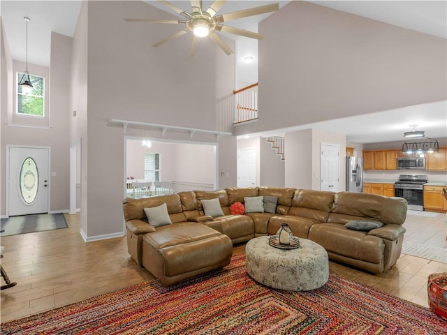 living area featuring plenty of natural light, light wood finished floors, ceiling fan, and high vaulted ceiling