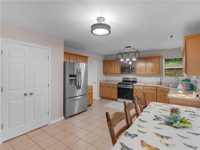kitchen with visible vents, light countertops, light tile patterned floors, a sink, and stainless steel appliances