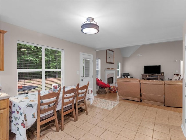 dining room with lofted ceiling, light tile patterned flooring, and a fireplace