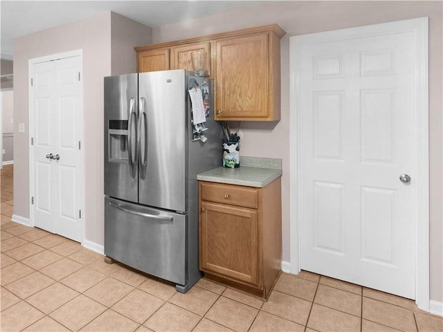 kitchen featuring baseboards, light tile patterned flooring, and stainless steel fridge with ice dispenser