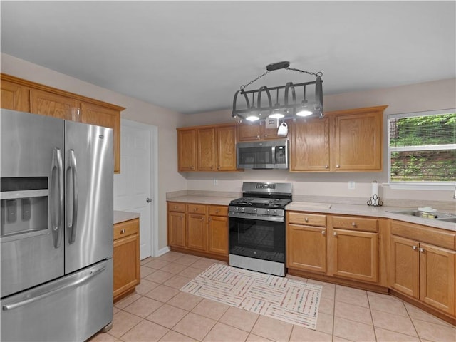 kitchen with light countertops, a sink, light tile patterned flooring, and stainless steel appliances