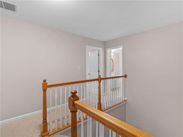 corridor featuring baseboards, carpet flooring, visible vents, and an upstairs landing