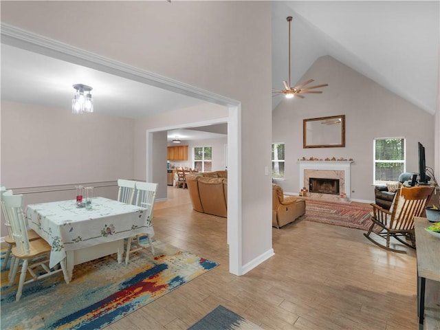 dining space featuring a high end fireplace, high vaulted ceiling, plenty of natural light, and light wood finished floors