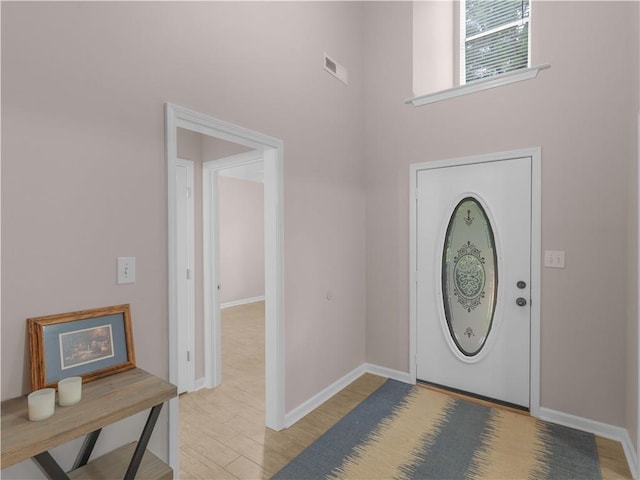 foyer featuring baseboards, visible vents, a high ceiling, and light wood-type flooring