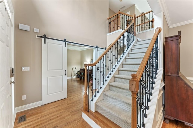 412 Mill Stream Way, Woodstock, GA 30188 - staircase featuring a barn door, ornamental molding, a high ceiling, wood finished floors, and baseboards