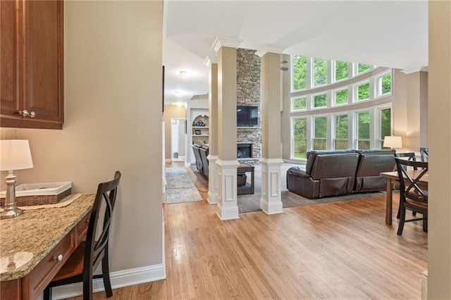 412 Mill Stream Way, Woodstock, GA 30188 - living area featuring ornate columns, crown molding, a stone fireplace, light wood-type flooring, and baseboards