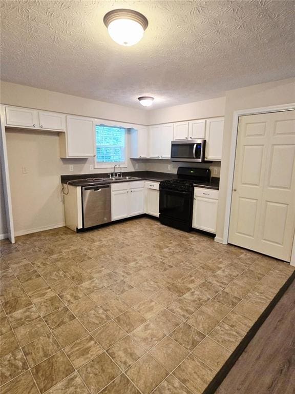 204 Twin Pines Ct, Dallas, GA 30132 - kitchen featuring appliances with stainless steel finishes, dark countertops, a sink, a textured ceiling, and white cabinets