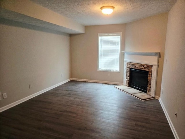 204 Twin Pines Ct, Dallas, GA 30132 - unfurnished living room with a textured ceiling, a stone fireplace, dark wood-style flooring, and baseboards