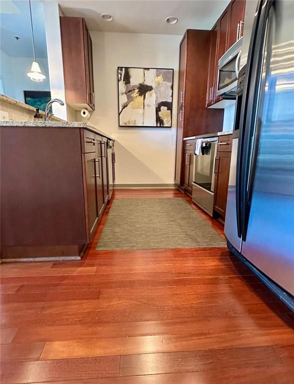 855 Peachtree St NE Unit 1406, Atlanta, GA 30308 - kitchen with stainless steel appliances, wood finished floors, light stone countertops, a sink, and hanging light fixtures