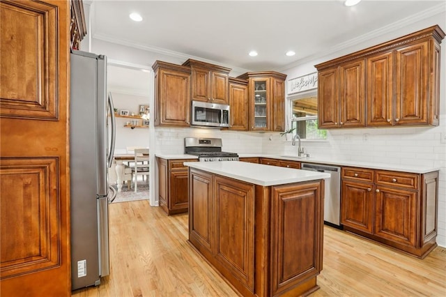 kitchen with light wood finished floors, a sink, light countertops, appliances with stainless steel finishes, and tasteful backsplash