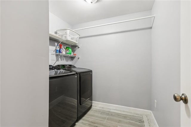 washroom featuring laundry area, independent washer and dryer, baseboards, and light wood-style floors