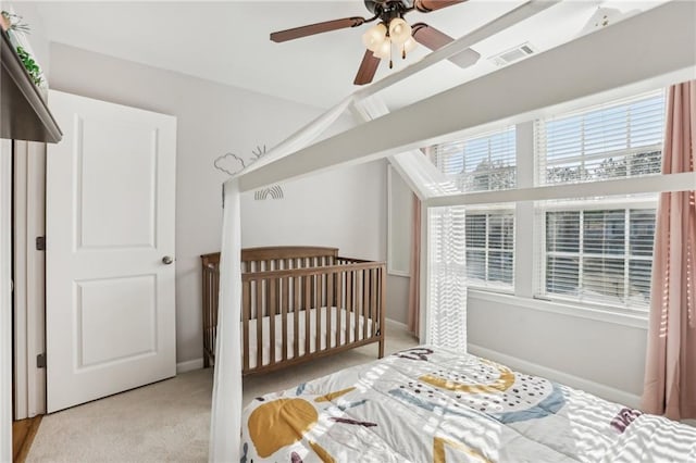carpeted bedroom featuring lofted ceiling, a nursery area, visible vents, ceiling fan, and baseboards