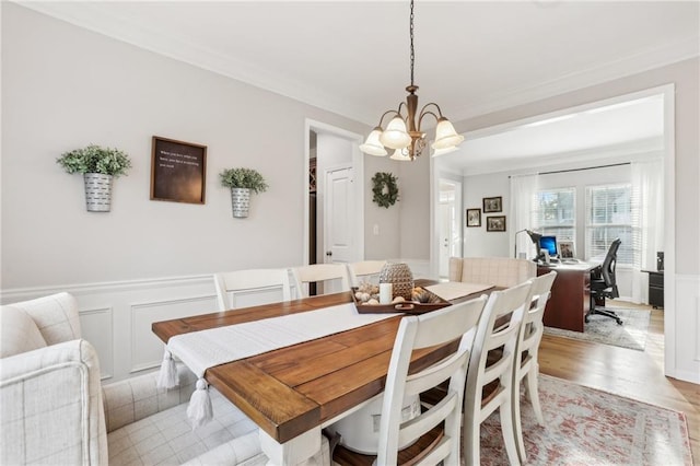 dining area featuring a chandelier, a decorative wall, and ornamental molding