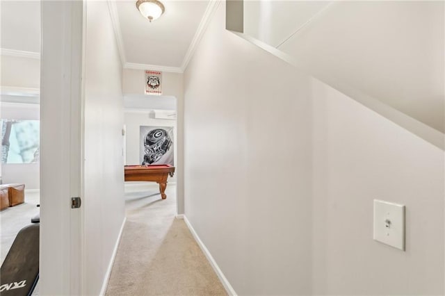 corridor featuring baseboards, ornamental molding, and light colored carpet