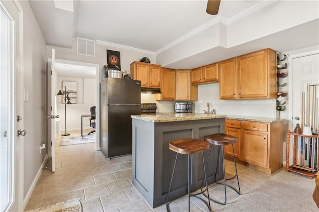 kitchen with freestanding refrigerator, crown molding, visible vents, baseboards, and range