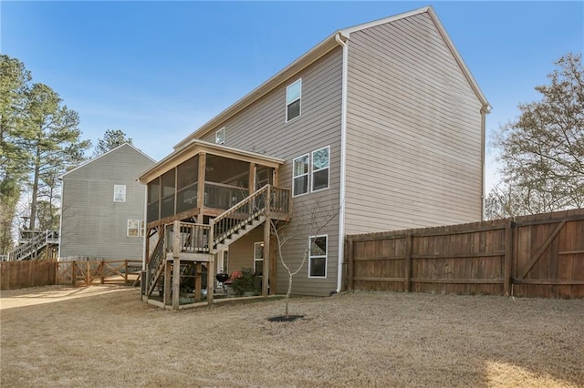 rear view of house with stairs, a sunroom, and a fenced backyard
