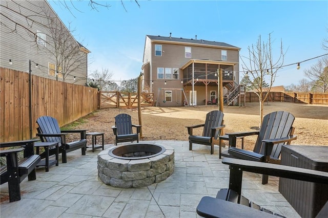 view of patio / terrace with a sunroom, stairway, a fire pit, and a fenced backyard