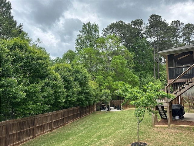 view of yard with a sunroom, a fenced backyard, and stairs