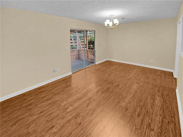 unfurnished room featuring an inviting chandelier and wood-type flooring