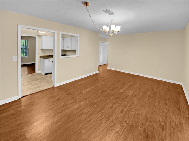 spare room featuring light wood-type flooring and an inviting chandelier