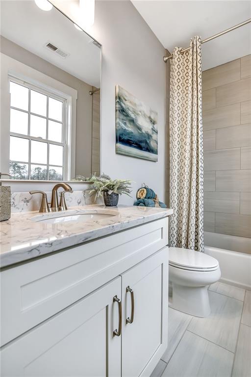 bathroom with toilet, vanity, shower / bathtub combination with curtain, and visible vents