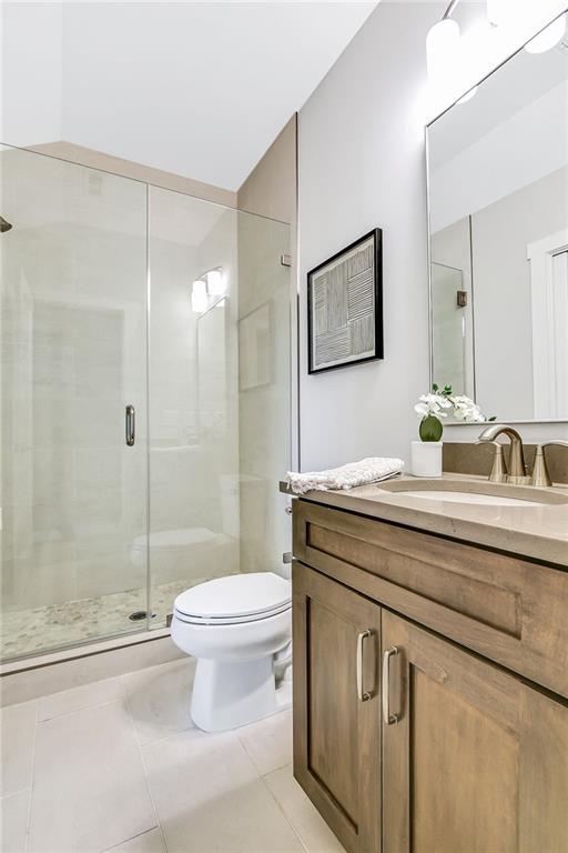 full bathroom with toilet, vanity, a stall shower, and tile patterned flooring