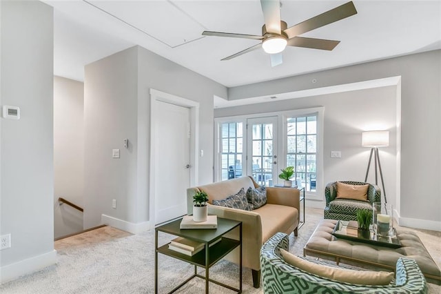living room featuring a ceiling fan, carpet floors, baseboards, and attic access