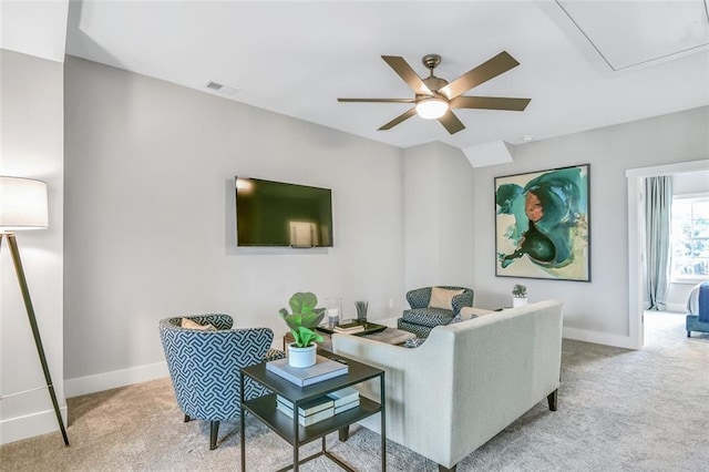 living area with baseboards, attic access, light colored carpet, and ceiling fan