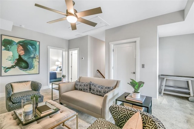 carpeted living area with a ceiling fan, attic access, and baseboards